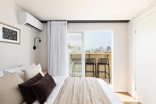 a bedroom with a bed and a balcony with chairs at AirTLV - Arlozorov Apartment's in Tel Aviv
