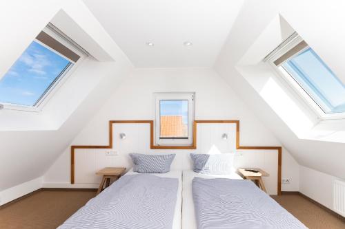 two beds in a attic bedroom with two windows at Fofftein in Juist