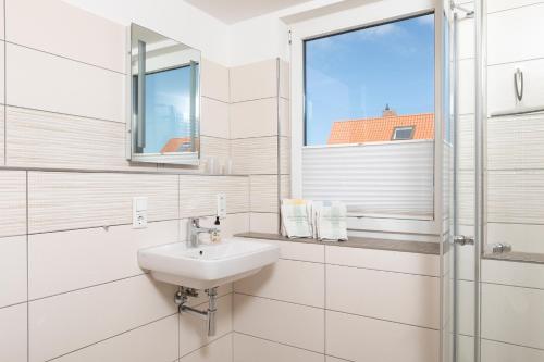 a white bathroom with a sink and a window at Fofftein in Juist