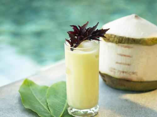 a drink in a glass next to a coconut at Explorar Koh Phangan - Adults Only Resort and Spa in Haad Rin