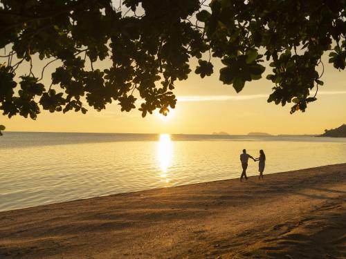 a couple walking on the beach at sunset at Explorar Koh Phangan - Adults Only Resort and Spa in Haad Rin