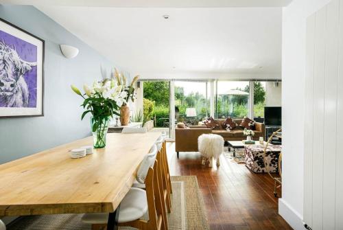 a dining room with a table and a living room with a couch at Roseberry Cottage - Lower Mill Estate in Somerford Keynes