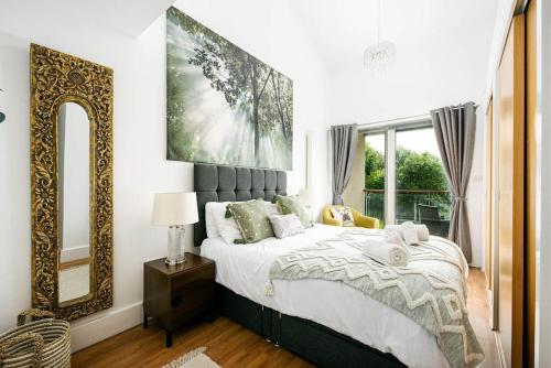 1 dormitorio con 1 cama grande y espejo en Roseberry Cottage - Lower Mill Estate, en Somerford Keynes