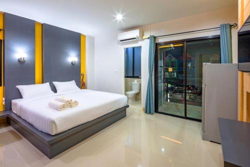 a bedroom with a white bed and a large window at Phoomjai Service Apartment in Ban Klang
