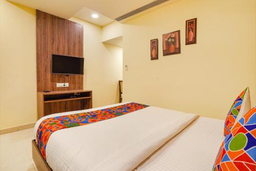 a bedroom with a bed and a flat screen tv at FabExpress Ginger Suites - Nr BHEL LTD in Bengaluru