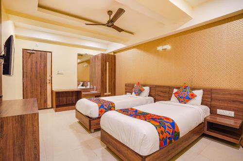 a bedroom with two beds and a ceiling fan at FabExpress Ginger Suites - Nr BHEL LTD in Bengaluru