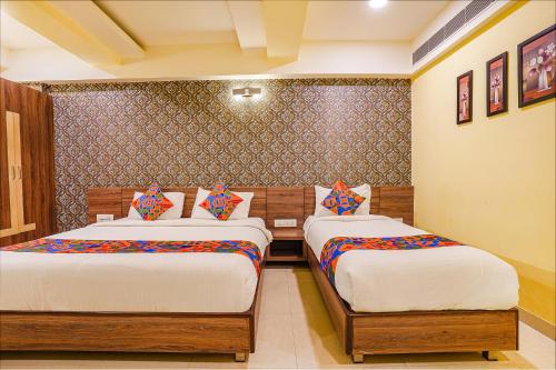 a bedroom with two beds and a wall at FabExpress Ginger Suites - Nr BHEL LTD in Bengaluru