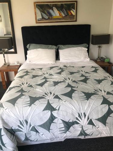 a bedroom with a bed with a black and white comforter at La Casita Waiheke in Oneroa