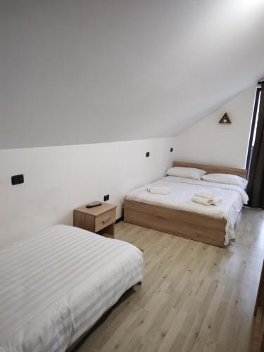two beds in a room with white walls and wooden floors at Vila Puiu Borsa MM in Borşa