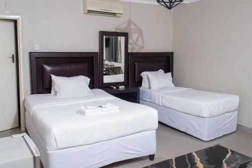 a bedroom with two beds with white sheets and a mirror at Fatmols City Hotel in Ndola