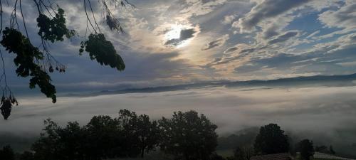 a view of a foggy valley with the sun in the clouds at Suite Villa Aurelj in Barolo