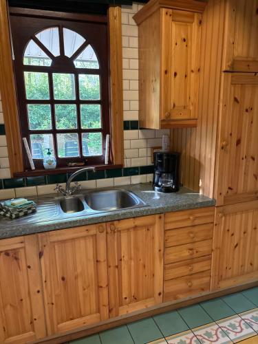 a kitchen with wooden cabinets and a sink at Witte wieven bungalow 17 in Nunspeet