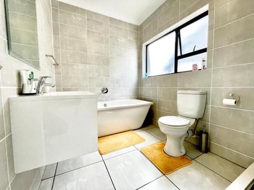 a bathroom with a toilet and a tub and a sink at TK’s Penthouse - The Blyde in Pretoria