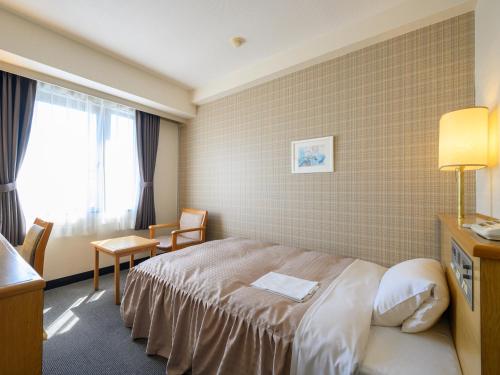 a hotel room with a bed and a window at Hotel Green Park Suzuka in Suzuka