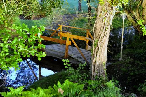 a wooden bridge over a river with a tree at Logis Hôtel Restaurant Relais Du Gué De Selle in Évron