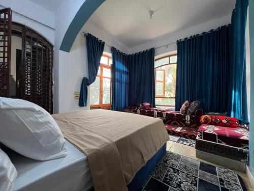 a bedroom with blue curtains and a bed and a couch at pyramids view Guest villa in Al Mazghūnah