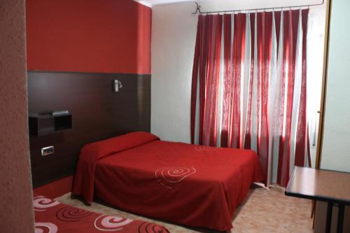 a small bedroom with a red bed and a window at Hostal Hellin in Miami Platja