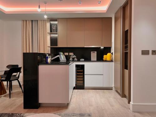 a kitchen with white and black cabinets and a table at Luxury 2 Bedroom Apartment in Old Street, London in London