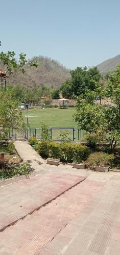 a park with a field and a fence and trees at Maruti Paradise Resort in Udaipur