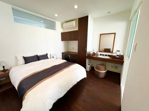 a bedroom with a bed and a desk and a mirror at NEXUS Ishinomakiokaidou in Ishinomaki