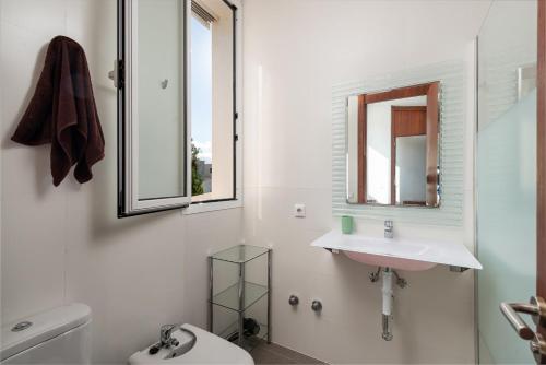 een badkamer met een wastafel, een toilet en een spiegel bij Domus Genti in Son Serra de Marina