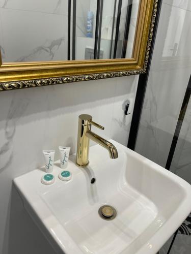 lavabo con grifo de oro y espejo en H&T Old Town Szeroka 36 en Gdansk