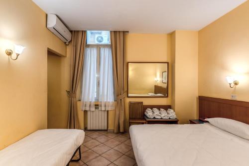 a hotel room with two beds and a mirror at Hotel Pomezia in Rome