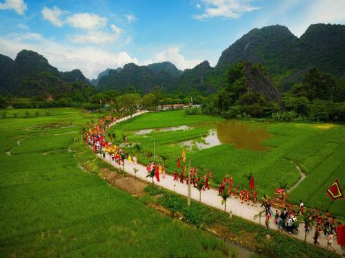 a group of people walking down a path in a field at Tam Coc Moutainside Homestay in Ninh Binh