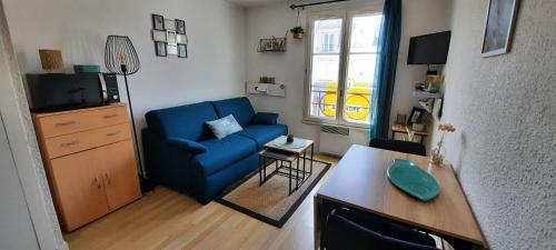 een woonkamer met een blauwe bank en een tafel bij Ty Cosy in Arzon