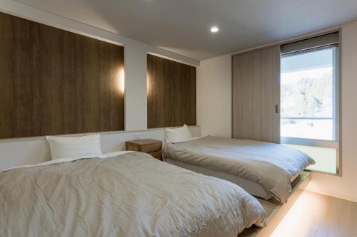 Kagamino的住宿－奧津溫泉米屋俱樂部旅館，一间卧室设有两张床和大窗户