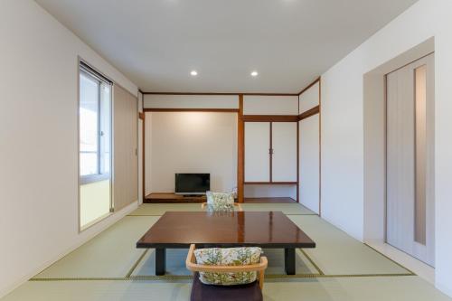 a living room with a table and a tv at Okutsu Onsen Komeya Club in Kagamino