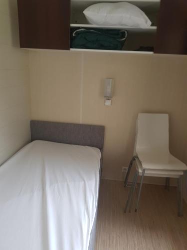- un lit et une chaise dans une petite pièce dans l'établissement Mobilhome Serre Ponçon, à Rochebrune