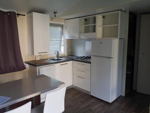 une cuisine avec des armoires blanches et un réfrigérateur blanc dans l'établissement Mobilhome Serre Ponçon, à Rochebrune
