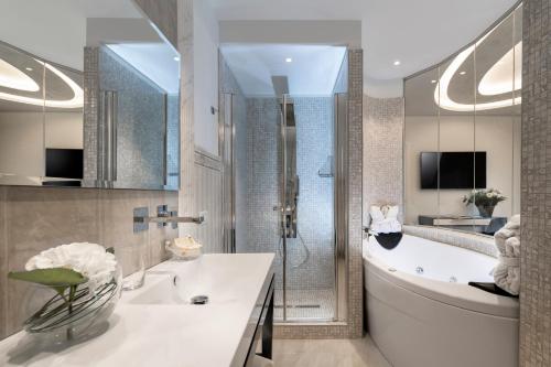 a bathroom with a tub and a sink and a shower at Grand Hotel Gallia in Milano Marittima