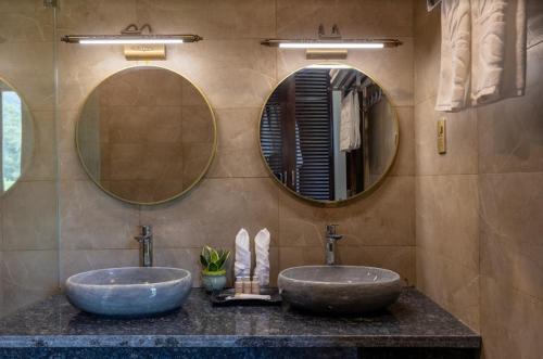 two sinks in a bathroom with two mirrors at Central hills Puluong resort in Hương Bá Thước