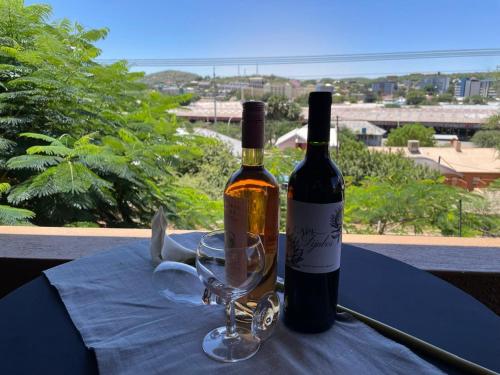 two bottles of wine and a glass on a table at Angelshof Self Catering Guesthouse in Windhoek