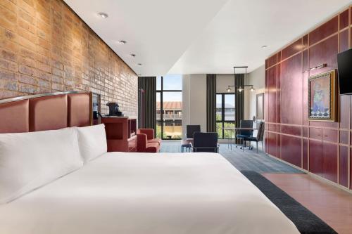 a bedroom with a large bed and a brick wall at African Pride Melrose Arch, Autograph Collection in Johannesburg