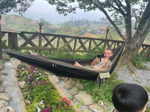 a man laying in a hammock looking at his cell phone at Pea homestay in Sa Pa