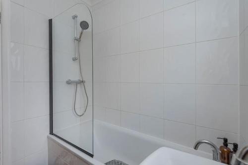 una ducha con una puerta de cristal junto a un lavabo en Gipsy Cottage with Sunny Garden and Conservatory, en West Dulwich