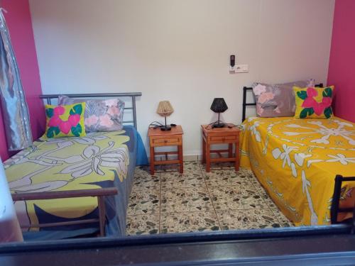een kamer met twee bedden en twee nachtkastjes bij CHEZ ALIZHIA in Nuku Hiva