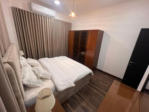 a small bedroom with a bed with white sheets at Ban Luxury Apartments in Al Khobar