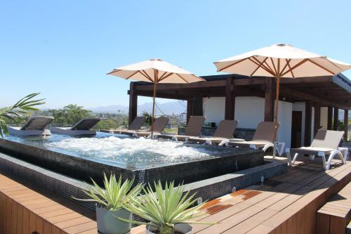 a pool with chairs and umbrellas on a deck at 105 Downtown cerca de playa y el malecón in Puerto Vallarta