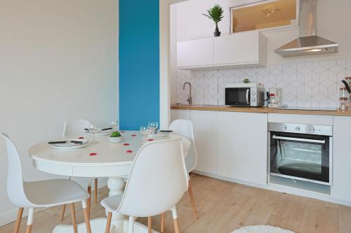 - une cuisine avec une table blanche et des chaises blanches dans l'établissement Évasion Pro & Fun à Saint-Étienne - Proche HPL, à Saint-Étienne