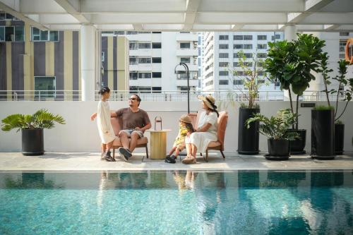 a group of people sitting next to a swimming pool at PARKROYAL Suites Bangkok - SHA Plus Certified in Bangkok
