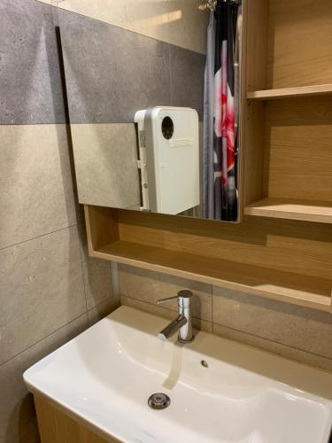 ein Waschbecken mit einem Spiegel und einem Seifenspender in der Unterkunft Charmante petite maison en pierre, avec accès autonome in Satillieu