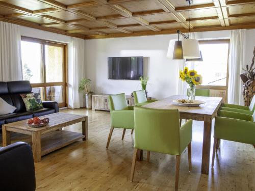- un salon avec une table et des chaises vertes dans l'établissement Cozy Apartment in Ruhmannsfelden with Swimming pool, à Achslach