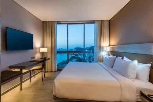 a hotel room with a large bed and a desk at AC Hotel By Marriott Santa Marta in Santa Marta