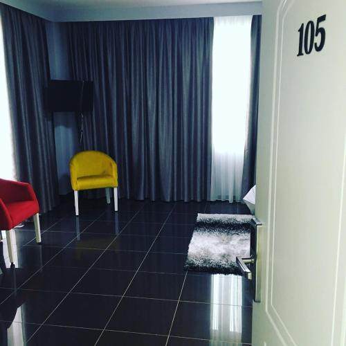 Zimmer mit gelbem Stuhl und Fenster in der Unterkunft Hotel Ascua in Tirana