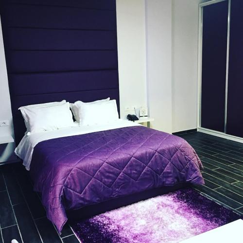 ein Schlafzimmer mit einem lila Bett mit einer lila Decke in der Unterkunft Hotel Ascua in Tirana