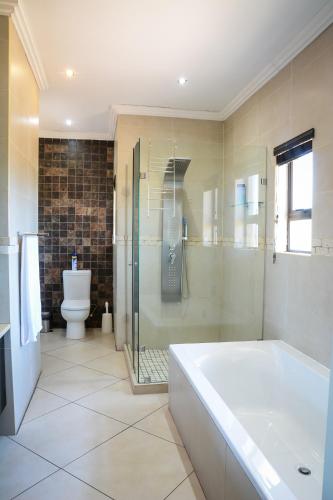 a bathroom with a tub and a shower and a toilet at 2916 on Egret - Parys Country and Golf Estate - Loadshedding friendly in Parys